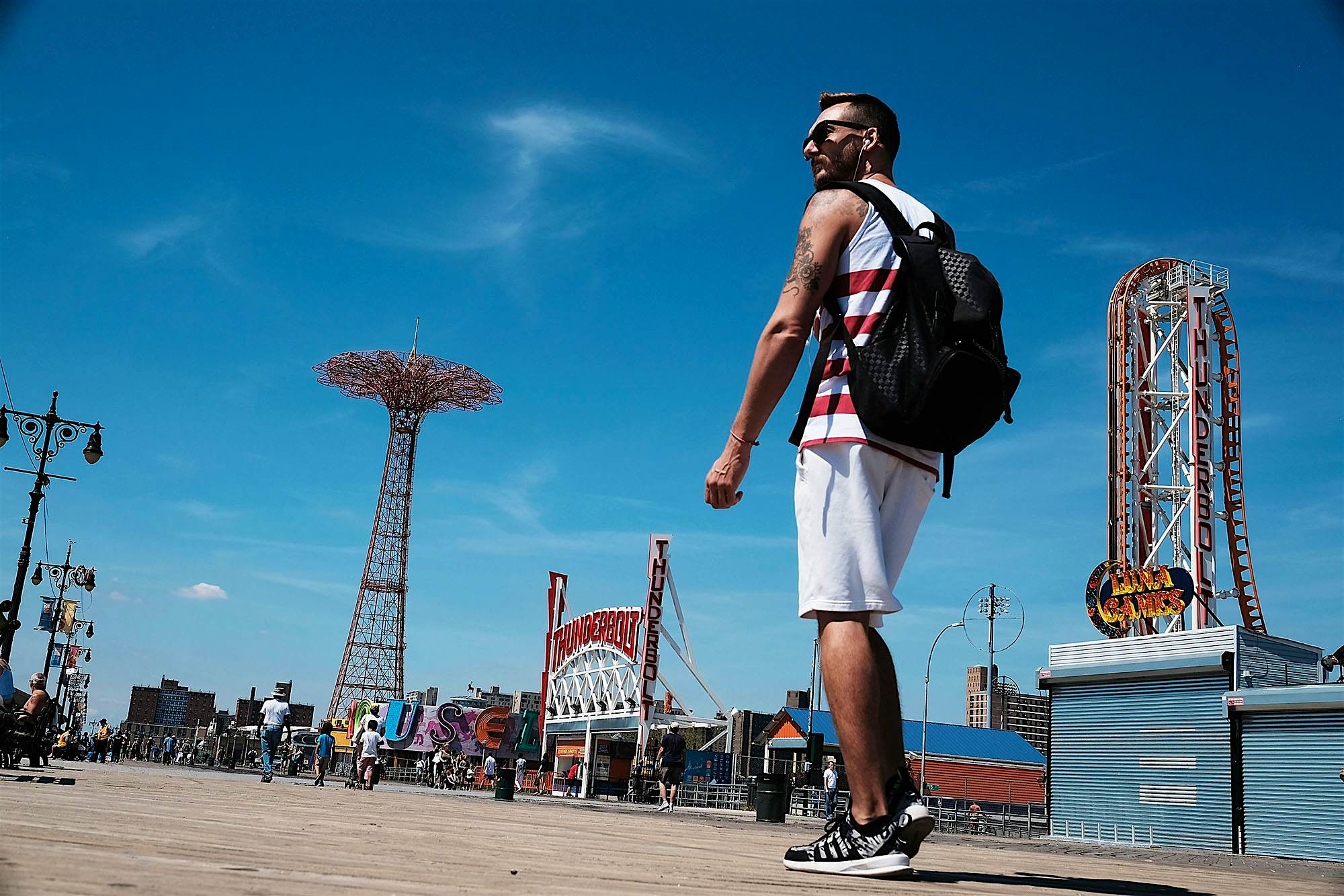 Travel News - Last Weeks Of Summer Embraced At New York's Coney Island Man walking in the sun at Coney Island Boardwalk