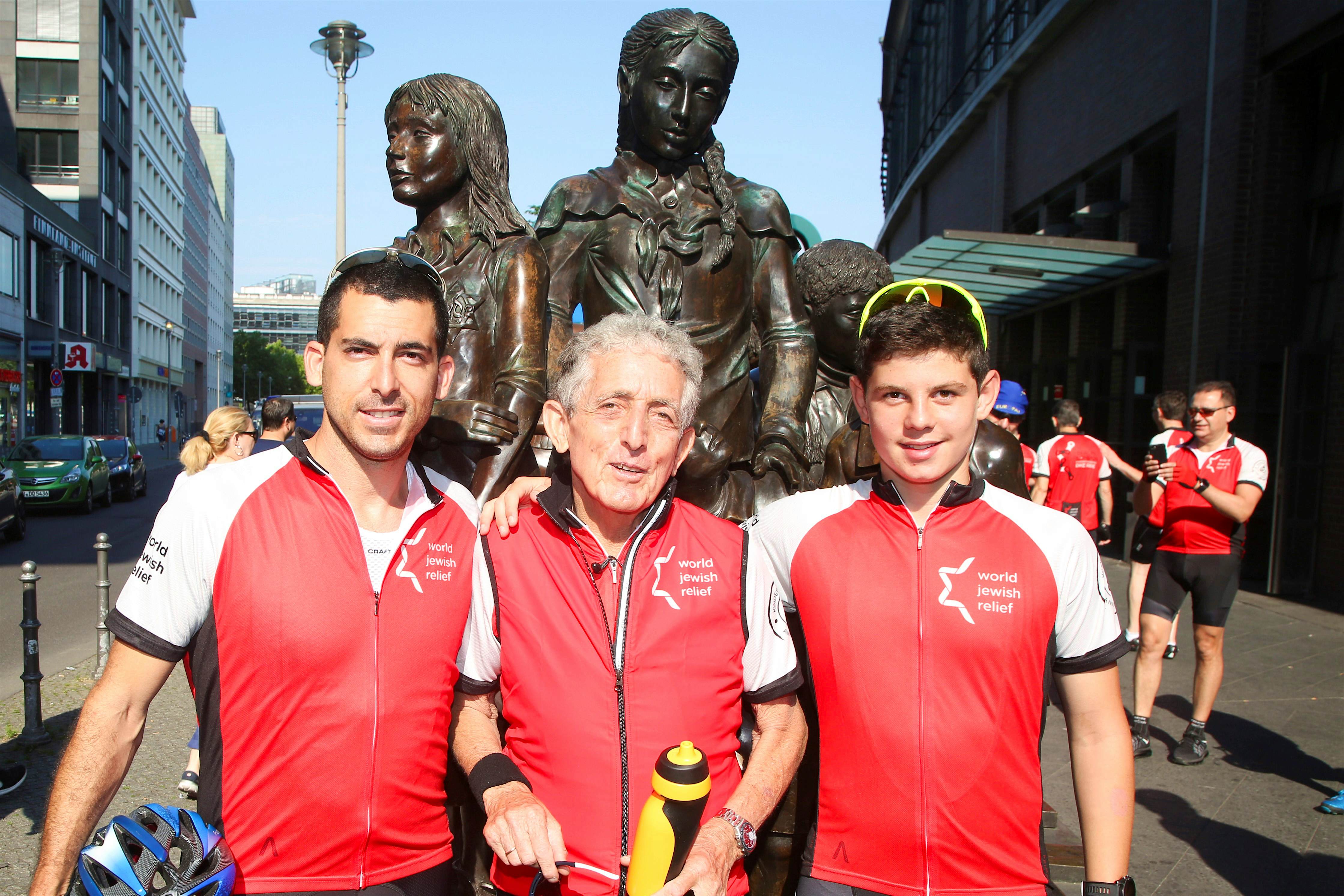 Travel News - Paul Alexander (centre) with his son Nadav (left) and grandson Daniel (right) at the Kindertransport statue in Berlin on the first day of the ride - photo credit - World Jewish Relief Travel News - Paul Alexander (centre) with his son Nadav (left) and grandson Daniel (right) at the Kindertransport statue in Berlin on the first day of the ride - photo credit - World Jewish Relief