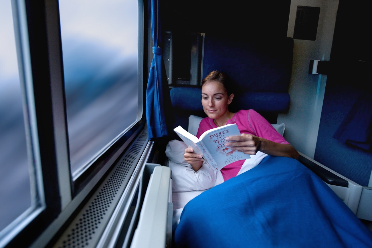 A women rading a book and resting in a roomette on an Amtrak train