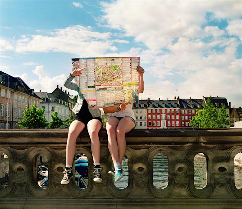 Dos personas se sientan en un puerto en Copenhague leyendo un mapa