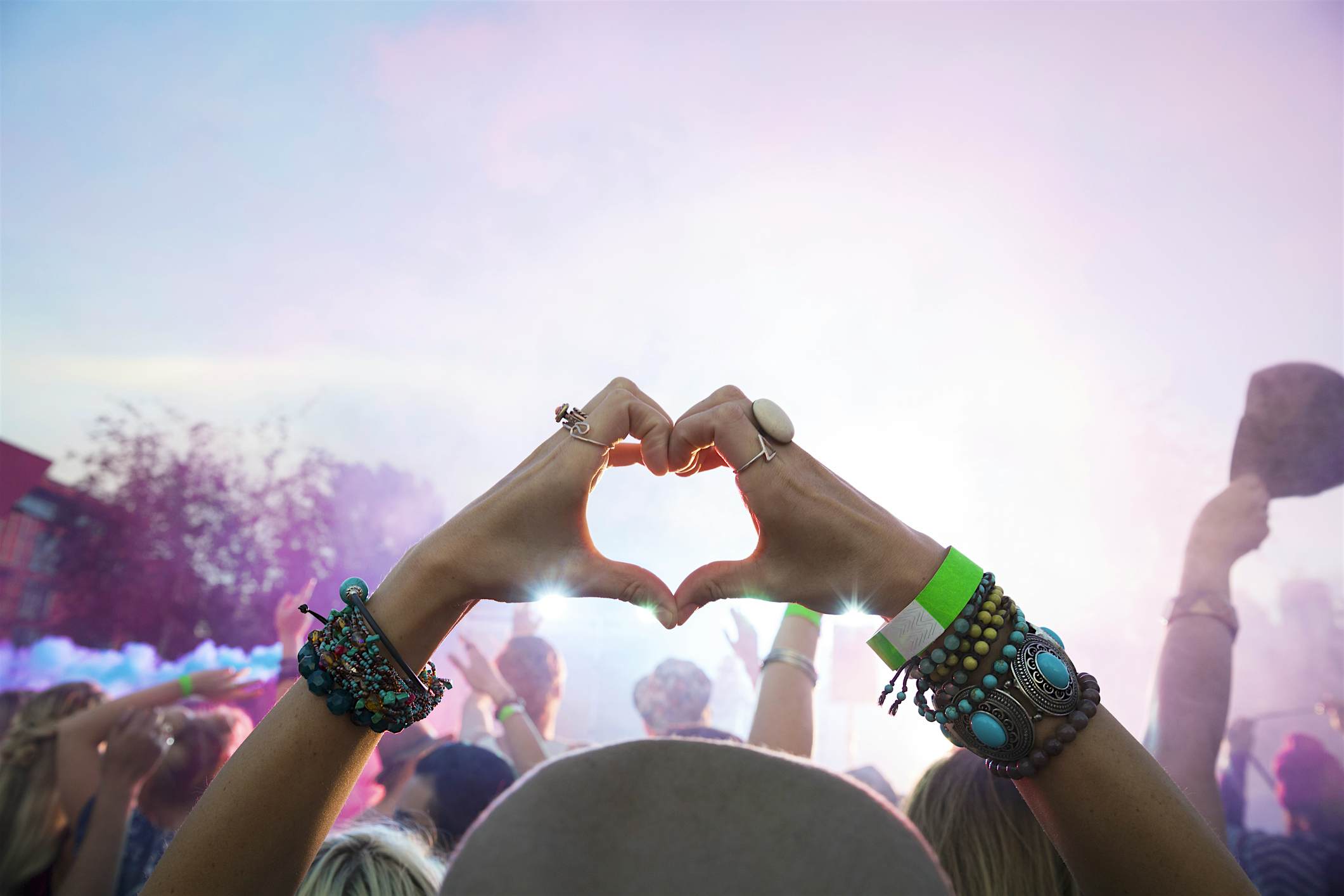 Travel News - Woman forming heart-shape with hands in crowd at summer music festival Travel News - Woman forming heart-shape with hands in crowd at summer music festival