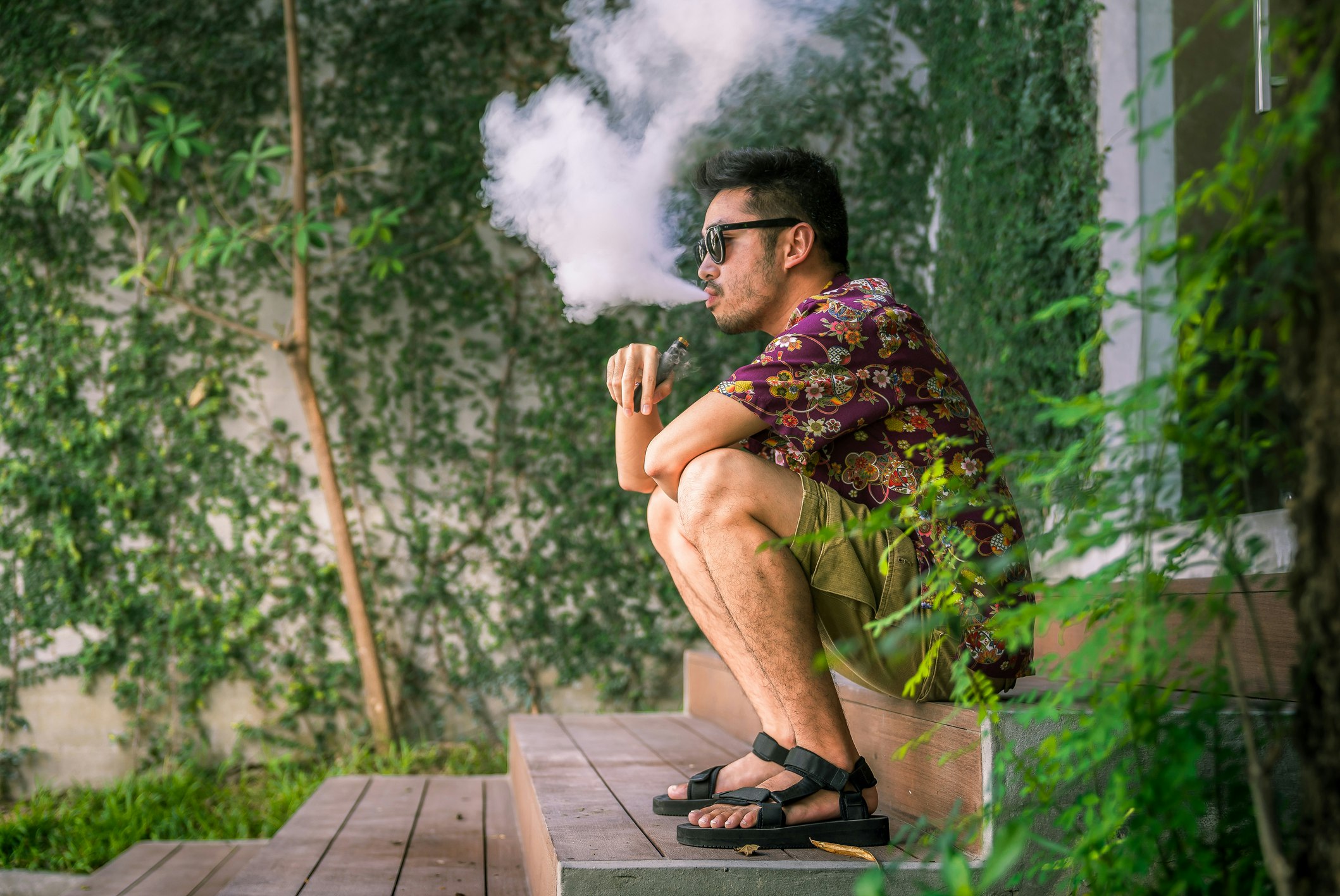 Man smoking an electric cigarette sitting on a step