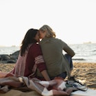Travel News - Tender, affectionate lesbian couple sitting on blanket on ocean beach