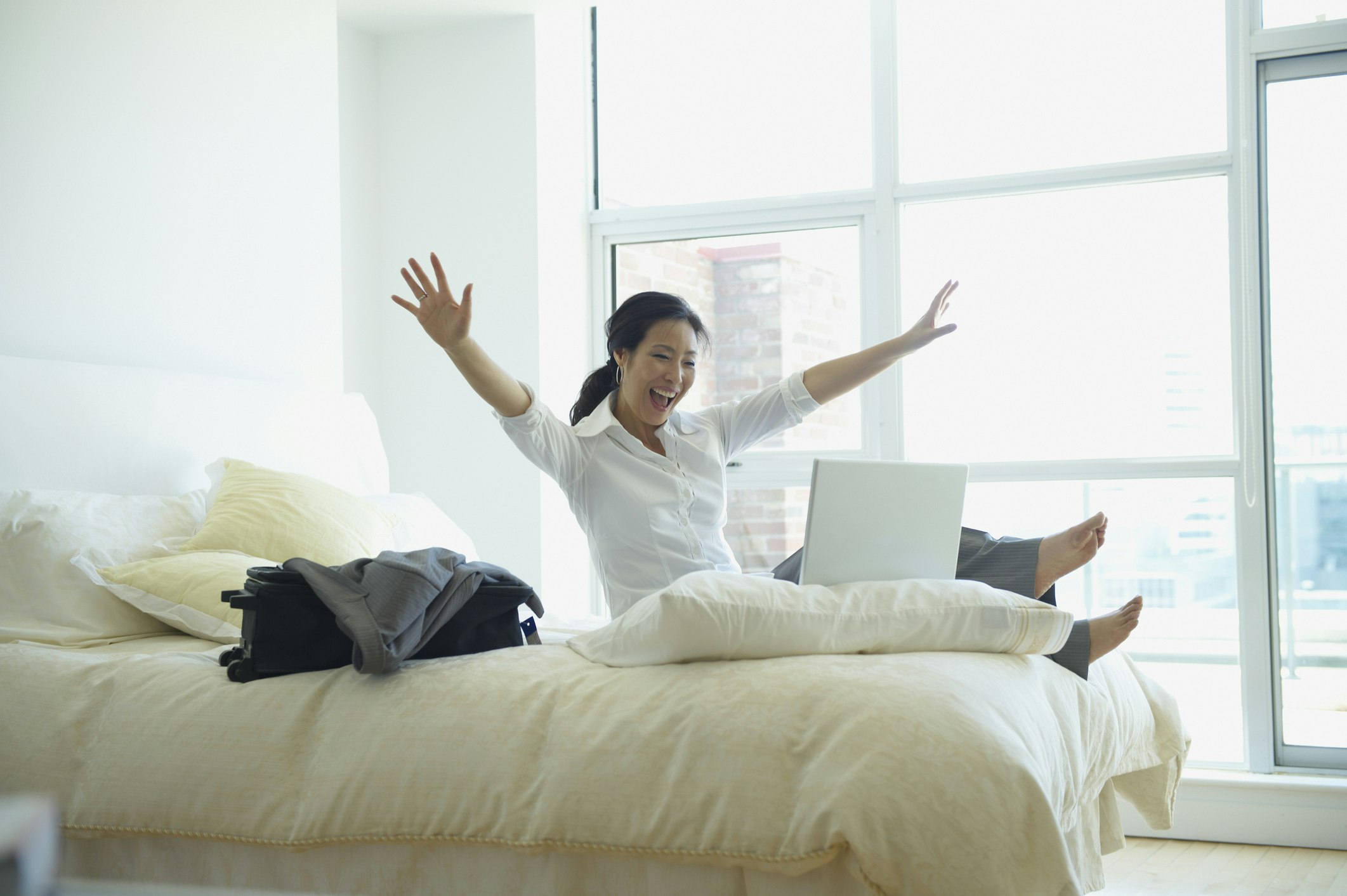 Travel News - Korean businesswoman working and cheering in hotel room