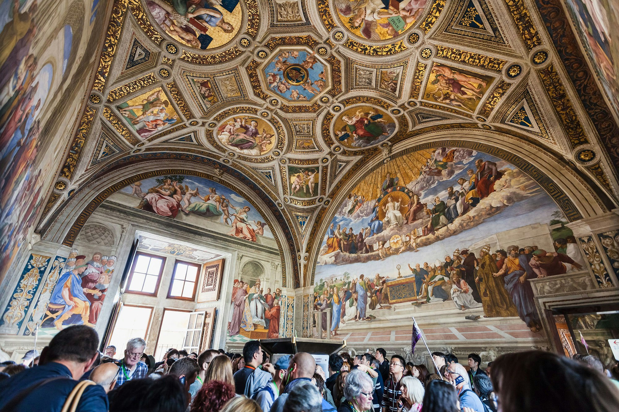 Visitors in Stanza della segnatura decorated by Raphael's frescoes in Raphael Rooms in Vatican Museums