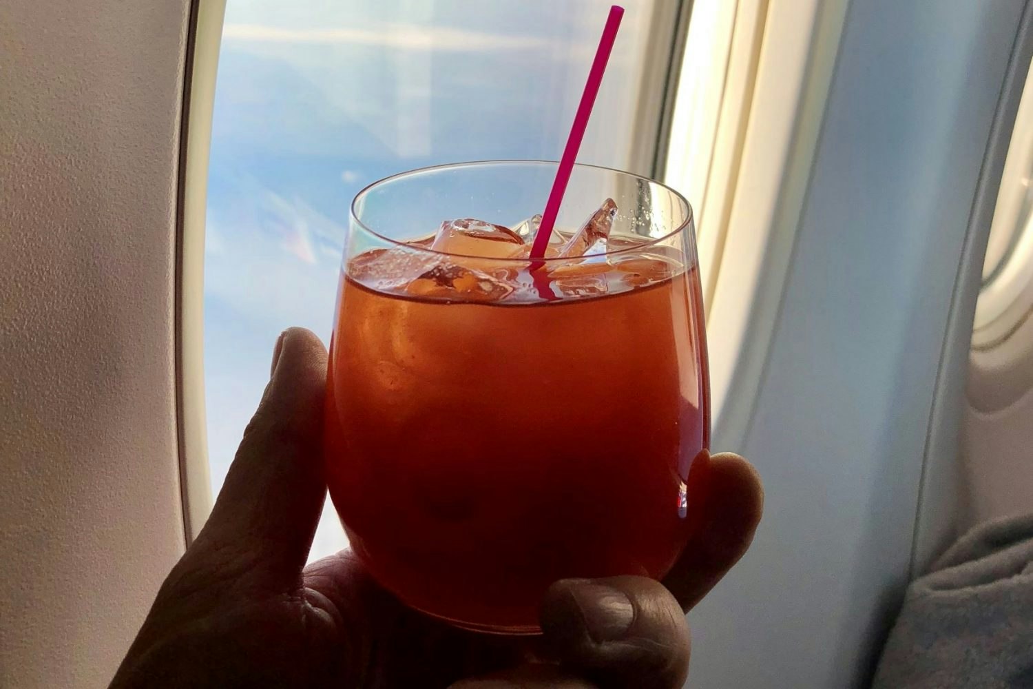 A hand holding a Bloody Mary on a plane