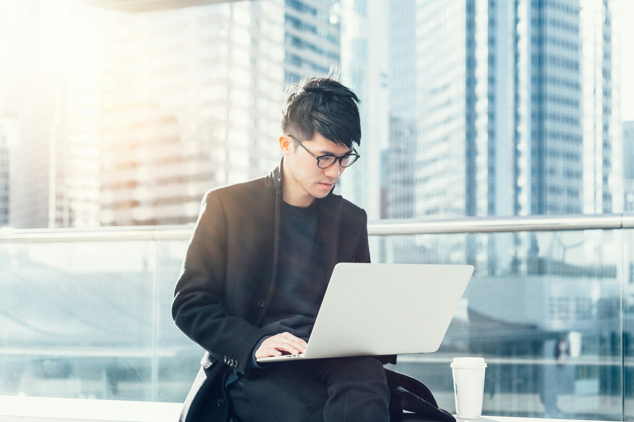 Travel News - Young businessman using laptop in hotel terrace