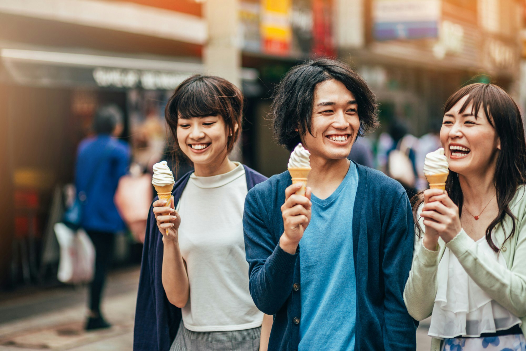 Three young people eating ice cream on the street in Japan.