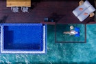An aerial view of a woman sleeping on a net suspended over the ocean in Grand Park Kodhipparu