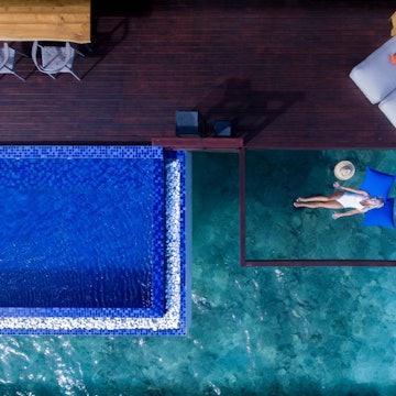 An aerial view of a woman sleeping on a net suspended over the ocean in Grand Park Kodhipparu