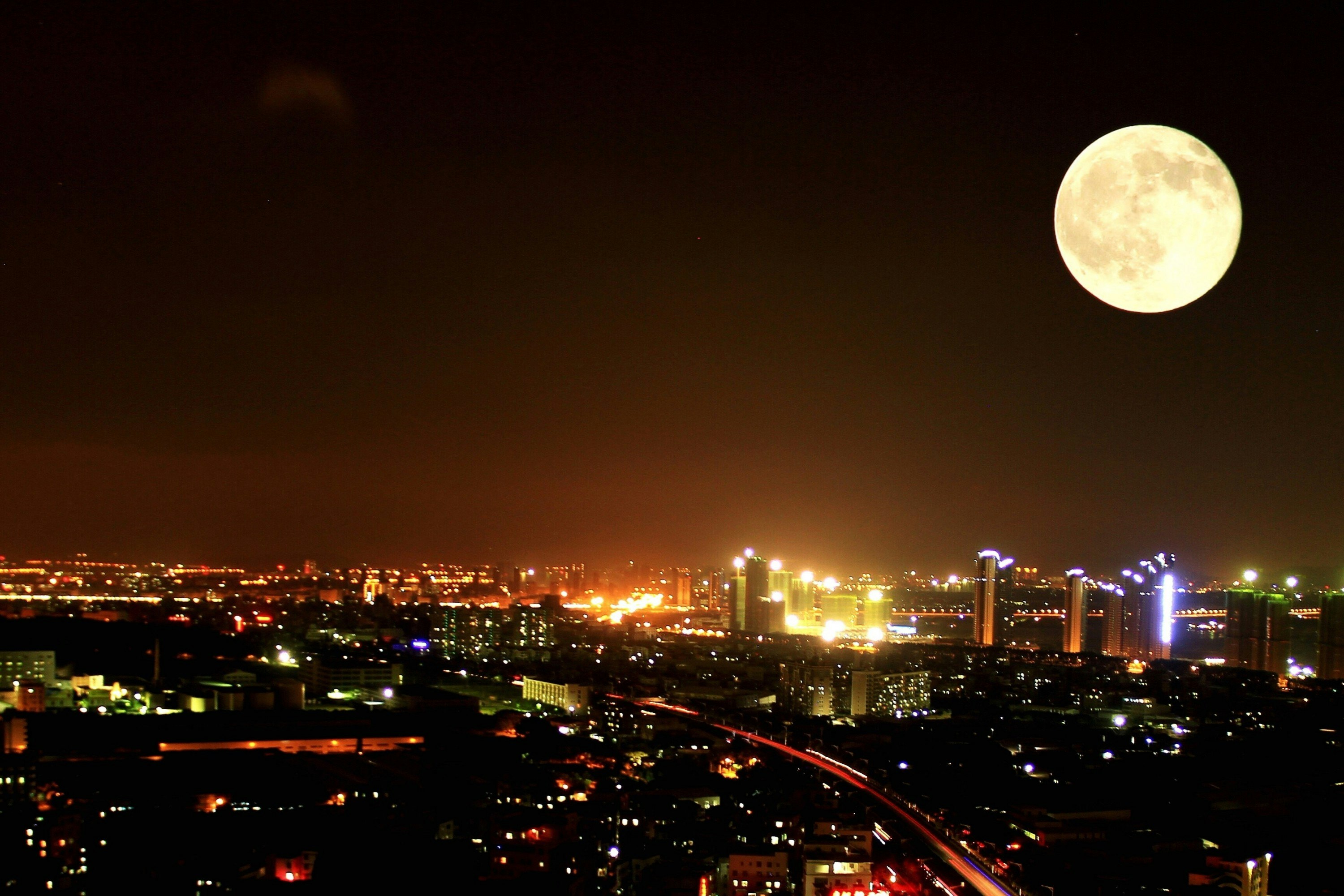 A full moon over a city at night.