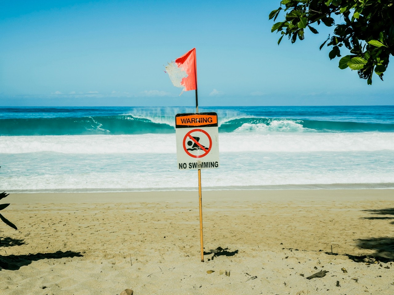 No swimming sign with flag at beach