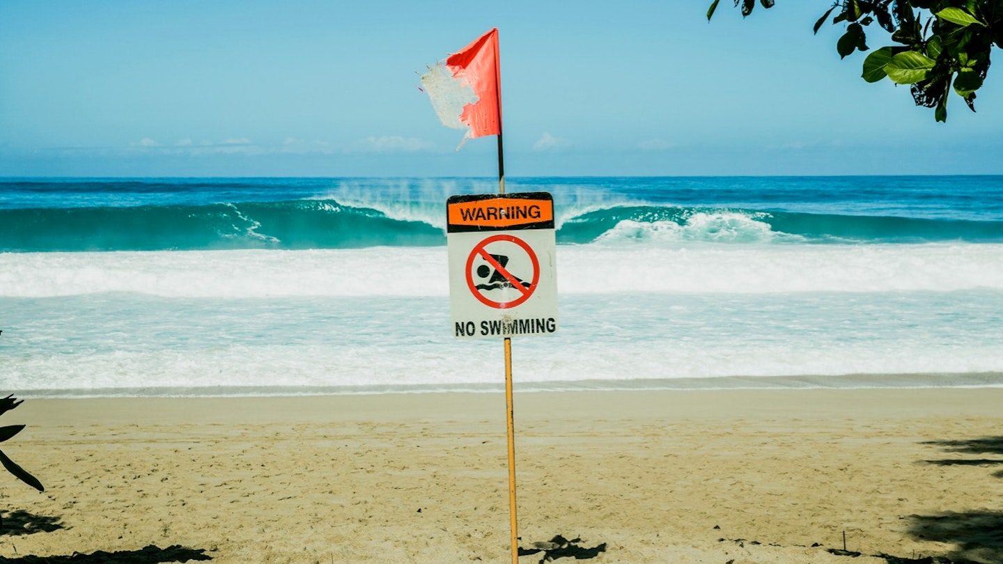 No swimming sign with flag at beach
