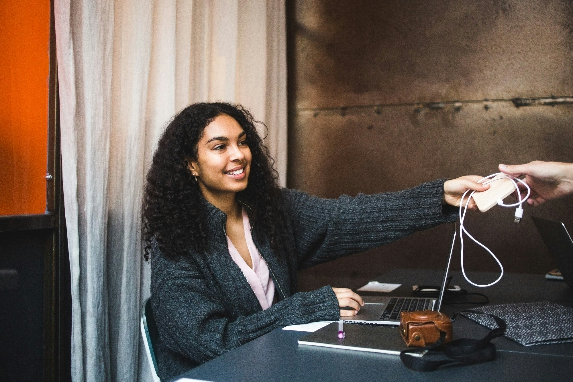 A woman borrowing a charger cable from somebody else