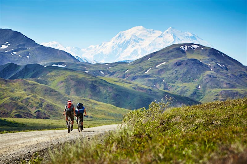 Travel News - Adult couple cycling on rural road, Mount McKinley, Denali National Park, Alaska, USA Adult couple cycling on rural road, Mount McKinley, Denali National Park, Alaska, USA