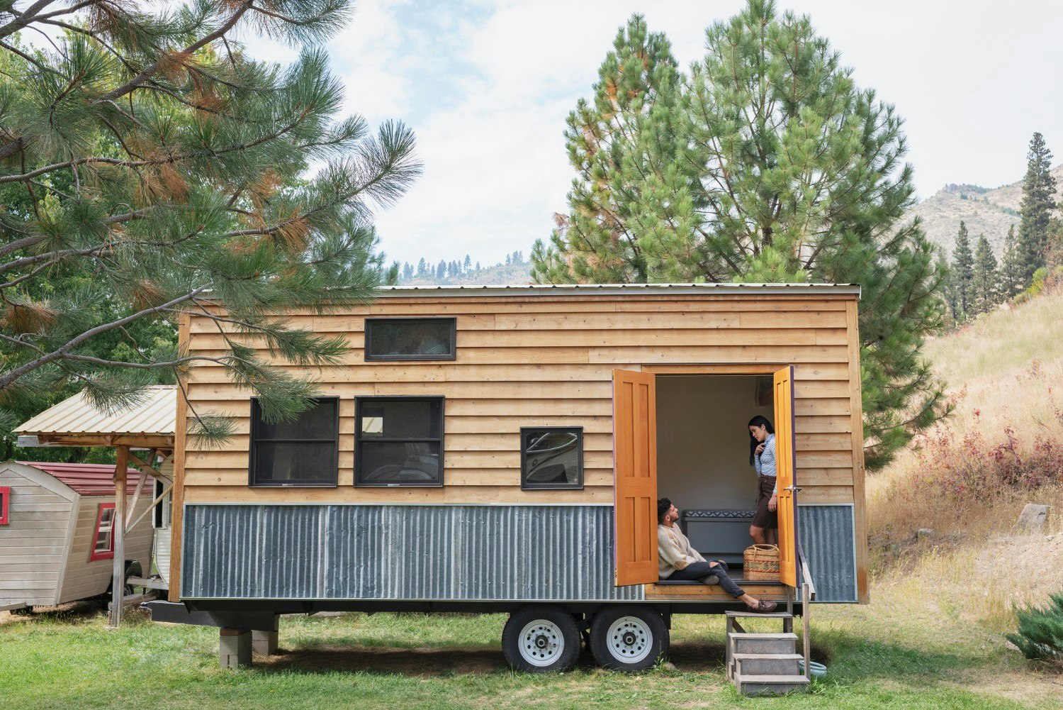 A young couple talking in the doorway of their tiny house