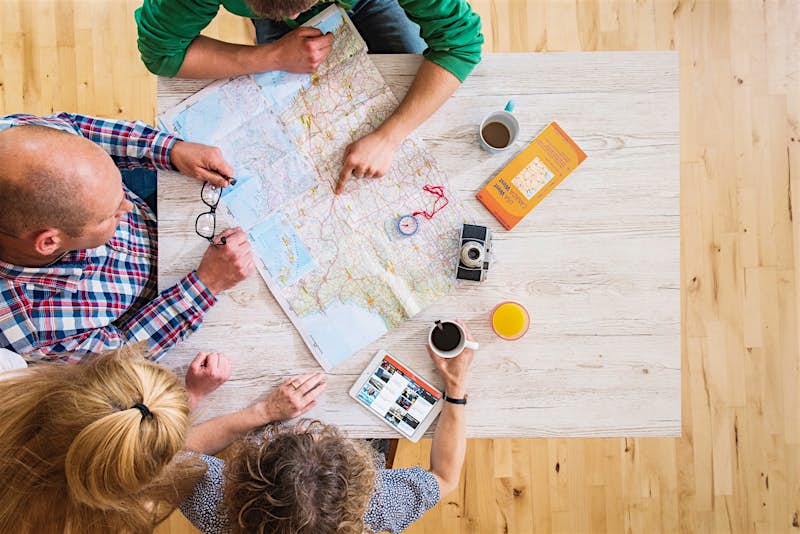 Travel News - family reading map at table family trip planning